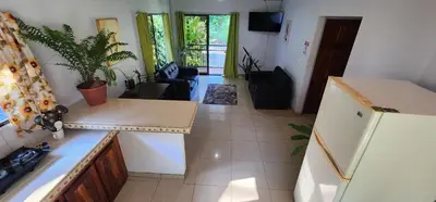 a kitchen with a refrigerator and a living room at El Retiro Del Bosque-Natural mystery in Manuel Antonio