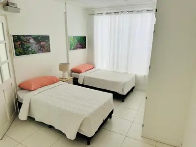a room with three beds and a window at Casa Pura Vida in Puntarenas