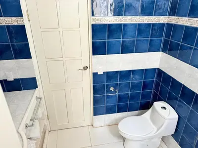 a bathroom with a toilet and blue tiled walls at Casa Pura Vida in Puntarenas