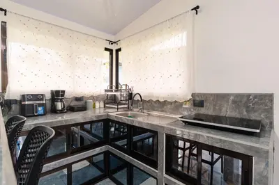 a kitchen with a sink and a counter with chairs at Villa Tucán Fortuna in Fortuna