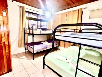 a room with three bunk beds and a window at Hostel La Perla in Puntarenas