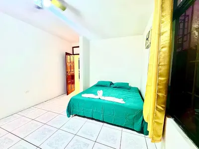 a bedroom with a green bed in a room at Hostel La Perla in Puntarenas