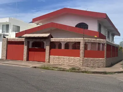 a red and white building with red doors on a street at Hostel la perla in Puntarenas