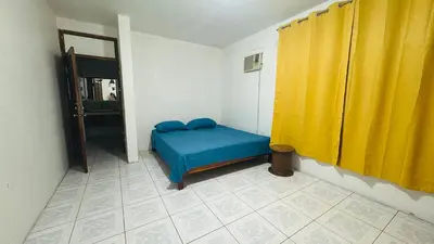 a bedroom with a blue bed and yellow curtains at Hostel la perla in Puntarenas