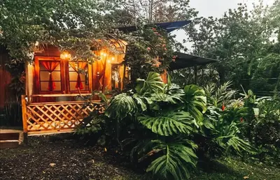 a small house with a red window and some plants at Natural - cabin, 30 min Fortuna, wifi 200mb in San Pedro