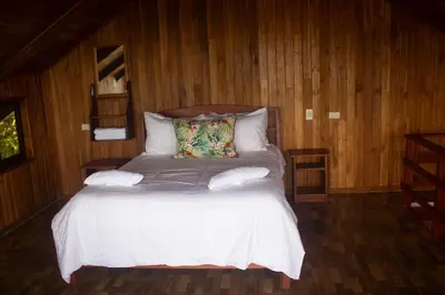a bed with white sheets and pillows in a room at Higuitos Lodge Cabaña in San Luis