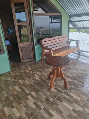 a wooden bench and a stool on a porch at Higuitos Lodge Cabaña in San Luis