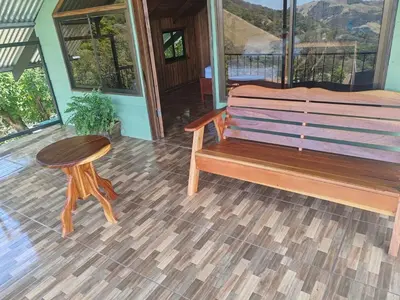a wooden bench and a table on a porch at Higuitos Lodge Cabaña in San Luis