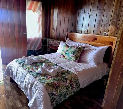 a bedroom with a bed with a wooden wall at Higuitos Lodge Cabaña in San Luis