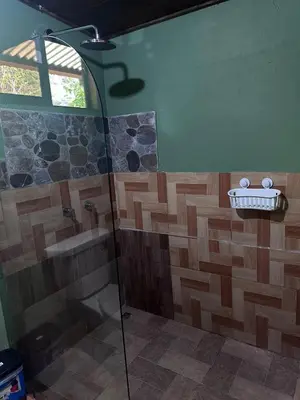 a bathroom with a shower with a glass door at Higuitos Lodge Cabaña in San Luis
