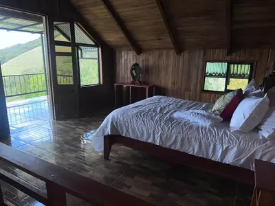 a bedroom with a bed and a large window at Higuitos Lodge Cabaña in San Luis