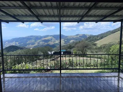 a view from the balcony of a house with mountains at Higuitos Lodge Cabaña in San Luis