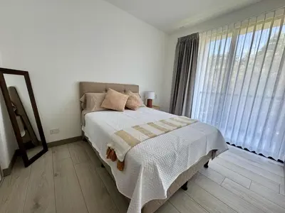 a white bedroom with a bed and a large window at Bosques de bambú in San José