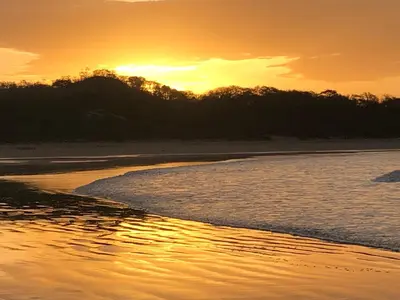 a sunset on a beach with the sun setting at Playa Grande, Las Baulas National Park BnB in Playa Grande