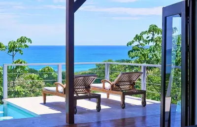 two chairs on a balcony looking out at the ocean at Luxury Ocean View Villa with Infinity pool in Santa Teresa Beach
