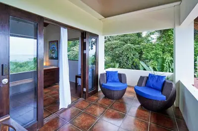 a room with two blue chairs and a balcony at Luxury Ocean View Villa with Infinity pool in Santa Teresa Beach