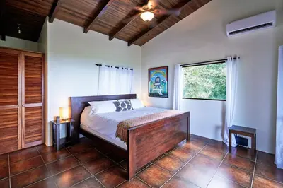 a bedroom with a bed and a large window at Luxury Ocean View Villa with Infinity pool in Santa Teresa Beach
