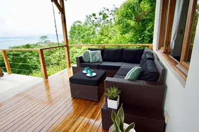 a screened in porch with a couch and a table at Luxury Ocean View Villa with Infinity pool in Santa Teresa Beach