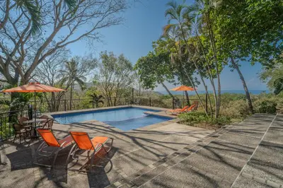 a swimming pool with orange chairs and umbrellas at Corozalito Turtle Inn in Nandayure