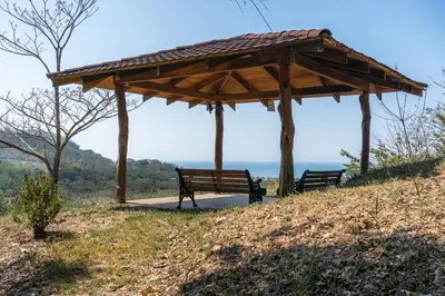 two benches sitting under a wooden pavilion on a hill at Corozalito Turtle Inn in Nandayure