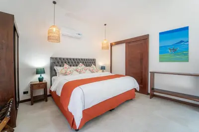 a bedroom with a large bed with orange and white sheets at Corozalito Turtle Inn in Nandayure