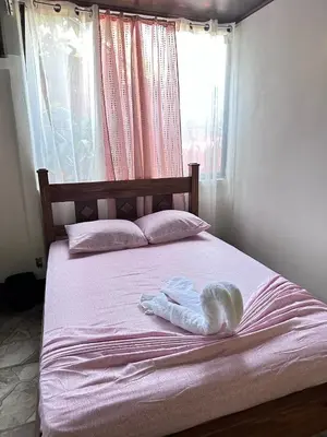 a bed with a towel on it with a window at Vacaciones en Tortuguero in Tortuguero