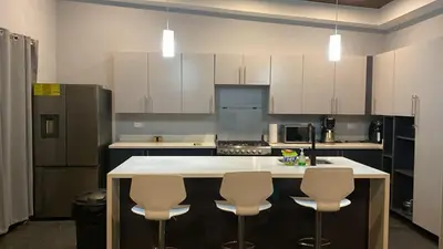 a kitchen with white cabinets and a island with bar stools at Villa Paradise in Guatemala