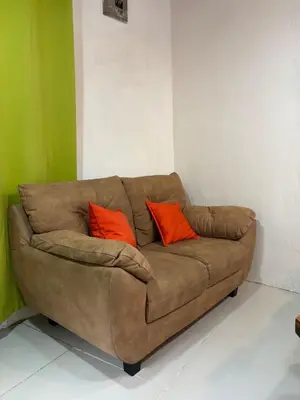 a brown couch with two orange pillows in a room at Steps by Monteverde in Monteverde Costa Rica