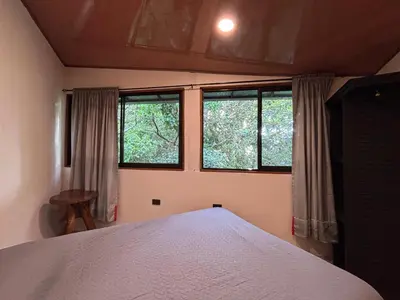 a bedroom with a bed and two windows at Steps by Monteverde in Monteverde Costa Rica
