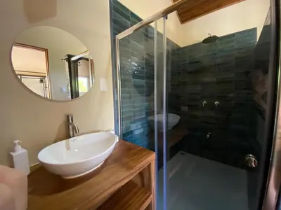 a bathroom with a sink and a glass shower at Casa Heliconia - Gorgeous Garden Home in Delicias in Puntarenas