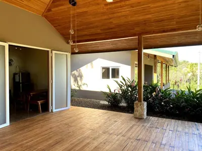 a porch with a wooden floor and a wooden ceiling at Casa Heliconia - Gorgeous Garden Home in Delicias in Puntarenas