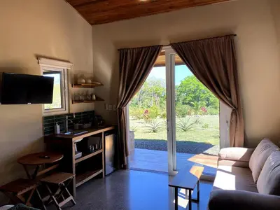 a living room with a couch and a table and a sliding glass door at Casa Heliconia - Gorgeous Garden Home in Delicias in Puntarenas