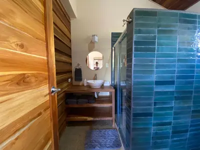 a bathroom with a sink and a shower with blue tiles at Casa Heliconia - Gorgeous Garden Home in Delicias in Puntarenas