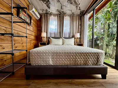 a bedroom with a bed and a large window at Tribu Bungalow 1 Modern and Centrally Located in Fortuna