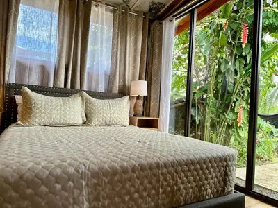 a bedroom with a bed and a large window at Tribu Bungalow 1 Modern and Centrally Located in Fortuna