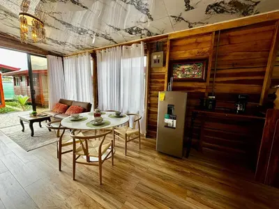 a living room with a table and a refrigerator at Tribu Bungalow 1 Modern and Centrally Located in Fortuna