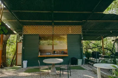 a green building with a table and chairs at Chilamate Rainforest Beach Retreat in Nosara