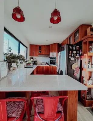 a kitchen with a counter and two red stools at Casa Solana in Puntarenas