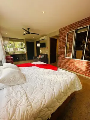 a large bed in a bedroom with a brick wall at Villa Alexandra in Punta Leona
