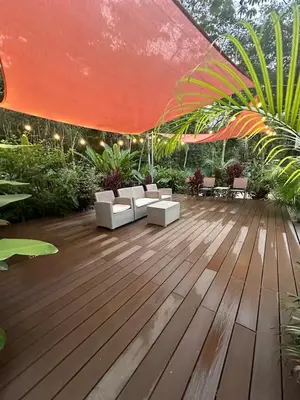 a wooden deck with chairs and a red umbrella at Villa Alexandra in Punta Leona