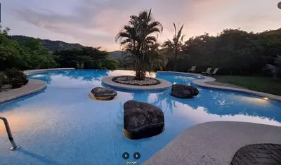 a swimming pool with a palm tree in the middle at Casa Fe- Newly Renovated 2 bedroom condo in Ocotal