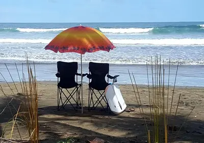 two chairs under an umbrella on the beach at Down by the Sea, the beachfront Apartment & Studio in Puerto Coyote