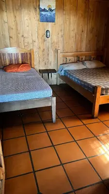 two beds in a room with wooden walls at Vista de montaña in Barva