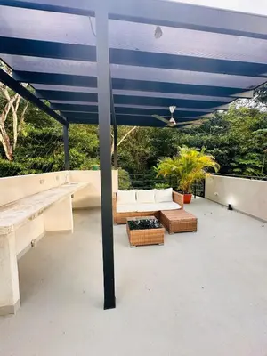 a blue umbrella on a patio with benches and tables at Villa Mary in Punta Leona