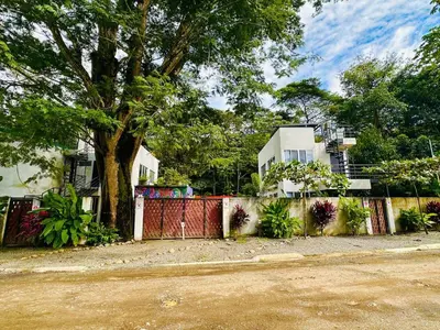 a fence with a tree in front of a house at Villa Mary in Punta Leona
