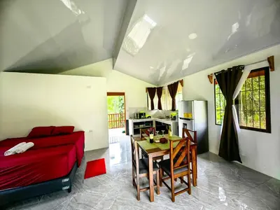 a bedroom with a bed and a table and a kitchen at Sloth House in San Isidro