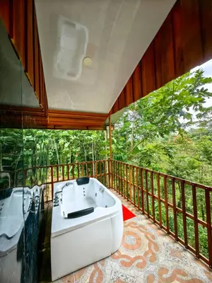 a bathroom with a tub and a balcony with trees at Sloth House in San Isidro