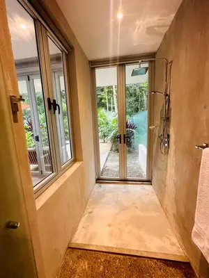 a bathroom with a walk in shower and a window at Villa Carol in Punta Leona