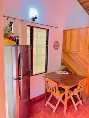 a kitchen with a wooden table and a refrigerator at Apartamentos El Labrador in Tamarindo