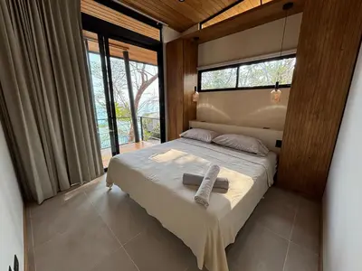 a bedroom with a bed in a room with windows at Mar a Cielo Brand New Ocean View Retreat in Mal País